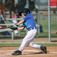 Little League baseball player connects with a pitch